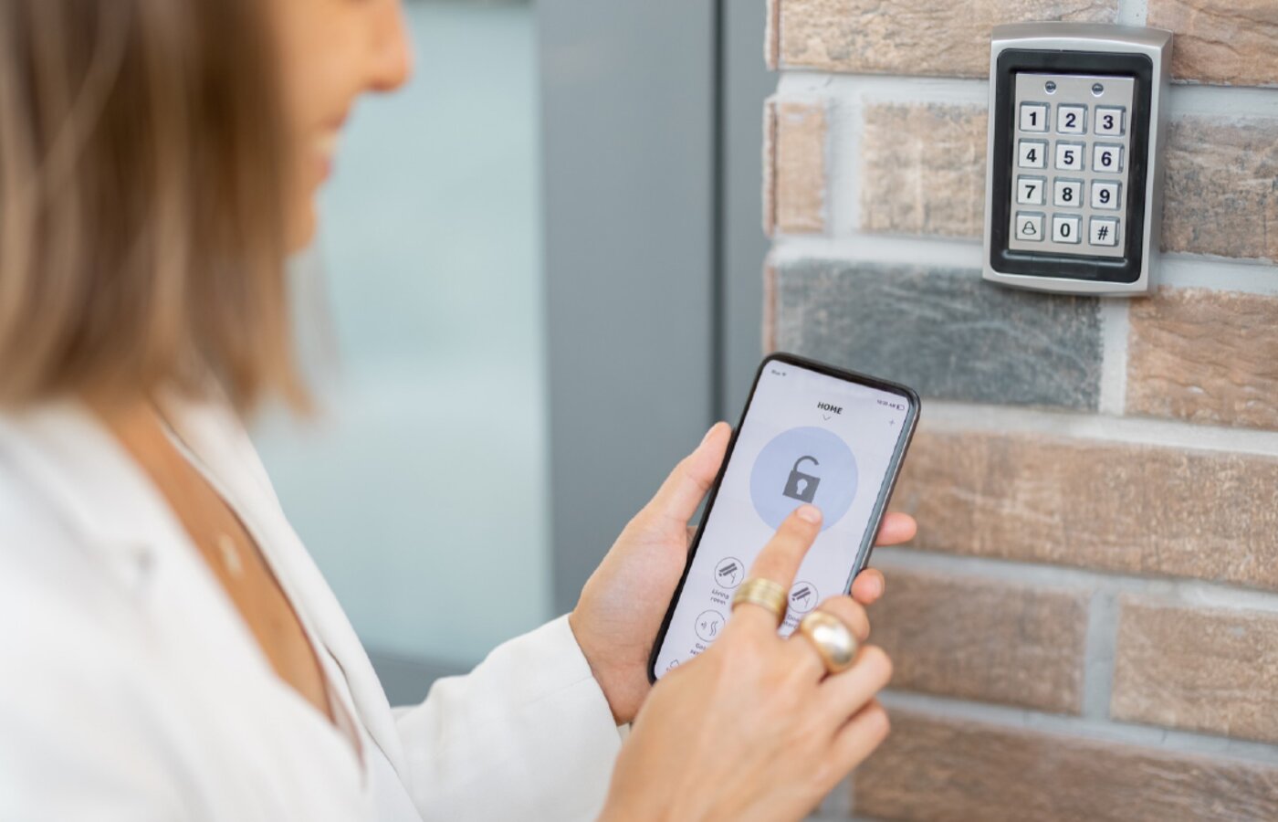 Person unlocking a door from a phone app beside a keypad and card reader